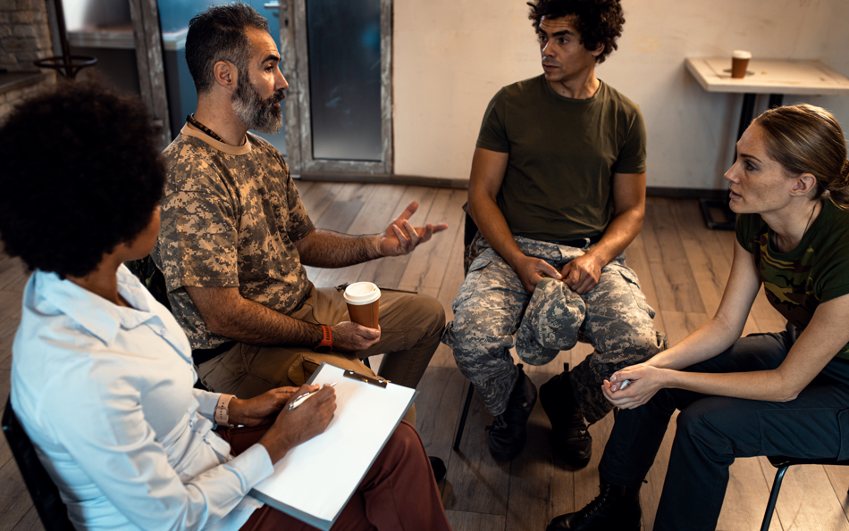 A group of diverse veterans sitting together at a table, reviewing documents with a medical expert.